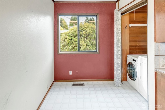 washroom with visible vents, washing machine and dryer, baseboards, light floors, and laundry area