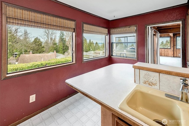 interior space featuring a sink, baseboards, tile patterned floors, and light countertops