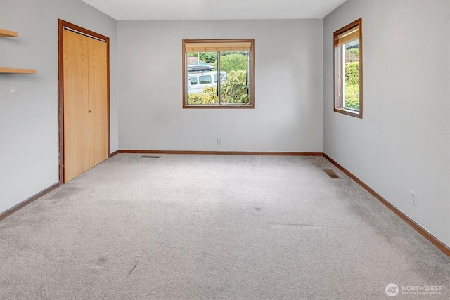 unfurnished bedroom featuring baseboards, visible vents, multiple windows, and carpet floors