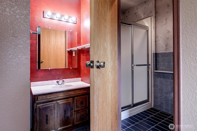 bathroom featuring a textured wall, vanity, a shower stall, and tile patterned flooring