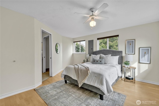 bedroom featuring baseboards, light wood-style floors, and a ceiling fan