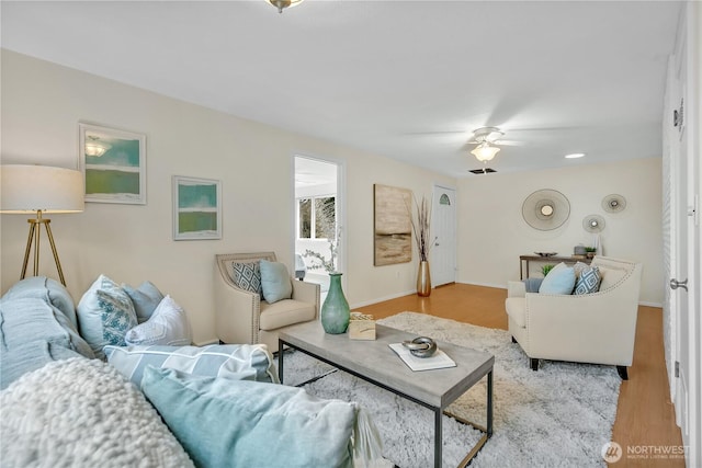 living room featuring ceiling fan, baseboards, and wood finished floors