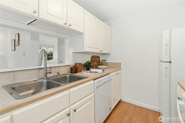 kitchen with white appliances, light countertops, light wood-type flooring, and a sink