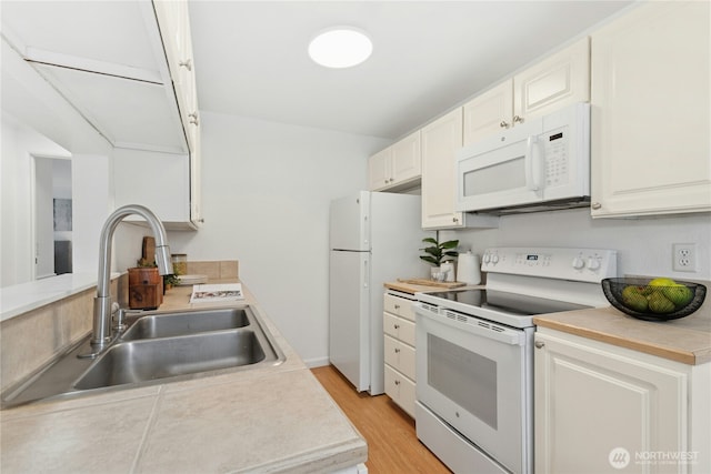 kitchen featuring light countertops, light wood-style floors, white cabinets, white appliances, and a sink