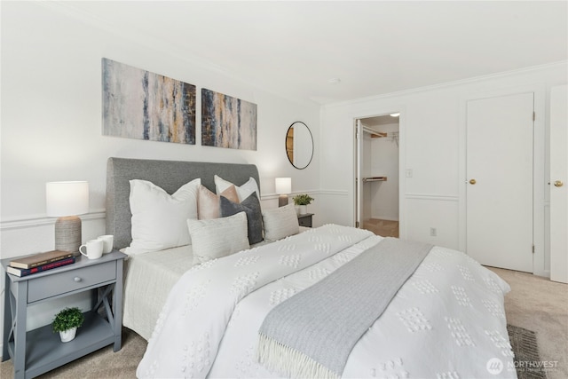 bedroom with light colored carpet, ornamental molding, and a spacious closet