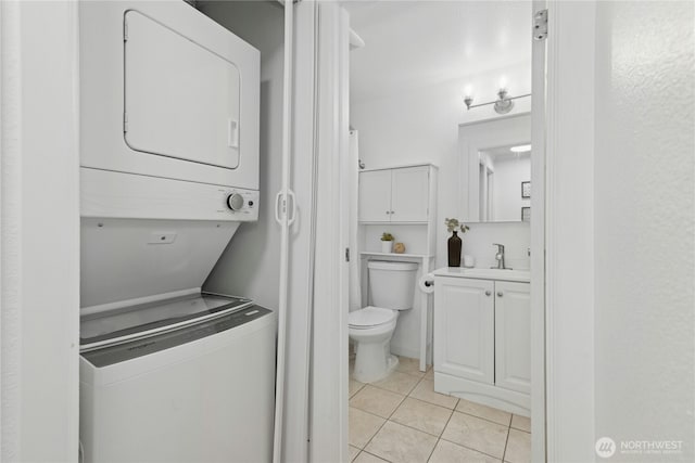 washroom featuring laundry area, stacked washer and dryer, light tile patterned flooring, and a sink