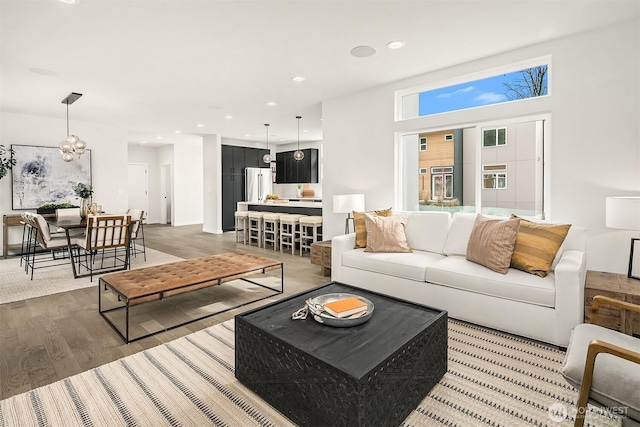 living room featuring a notable chandelier, recessed lighting, and light wood-style floors