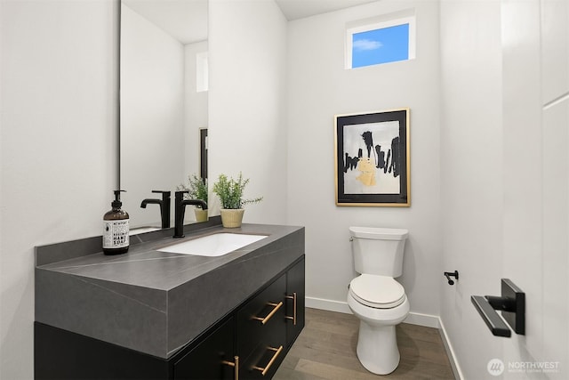 half bathroom featuring baseboards, toilet, wood finished floors, and vanity