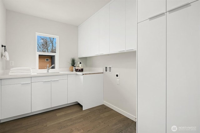 laundry area featuring electric dryer hookup, a sink, cabinet space, hookup for a washing machine, and dark wood-style flooring