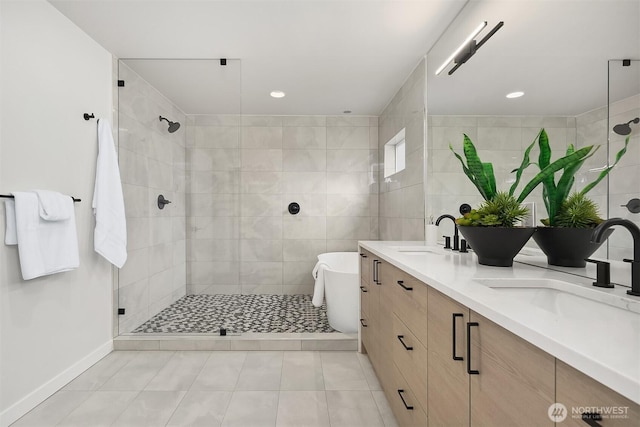 bathroom featuring double vanity, a tile shower, and a sink