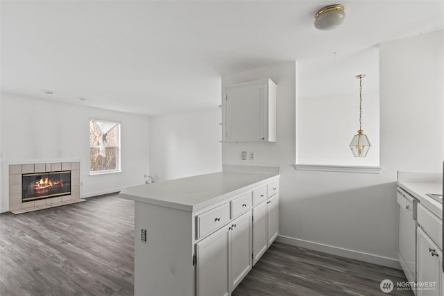 kitchen featuring a peninsula, baseboards, dishwasher, and dark wood-type flooring