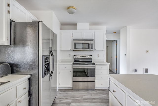 kitchen with appliances with stainless steel finishes, white cabinetry, and light countertops