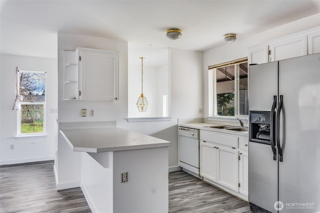 kitchen with a peninsula, open shelves, stainless steel fridge with ice dispenser, white dishwasher, and a sink