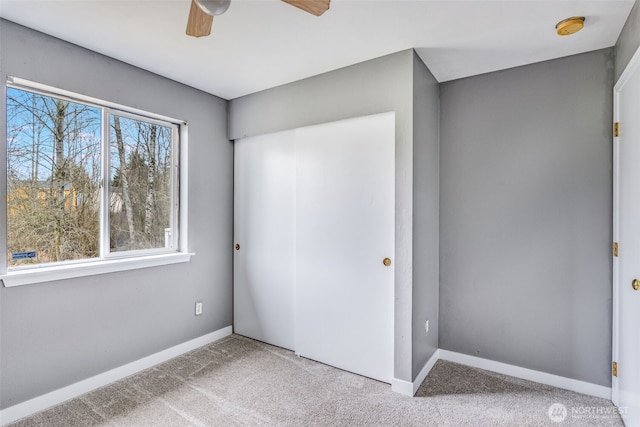 unfurnished bedroom with a closet, baseboards, a ceiling fan, and carpet flooring