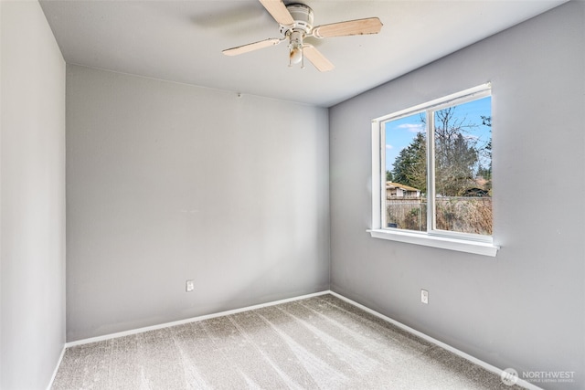 carpeted spare room featuring ceiling fan and baseboards