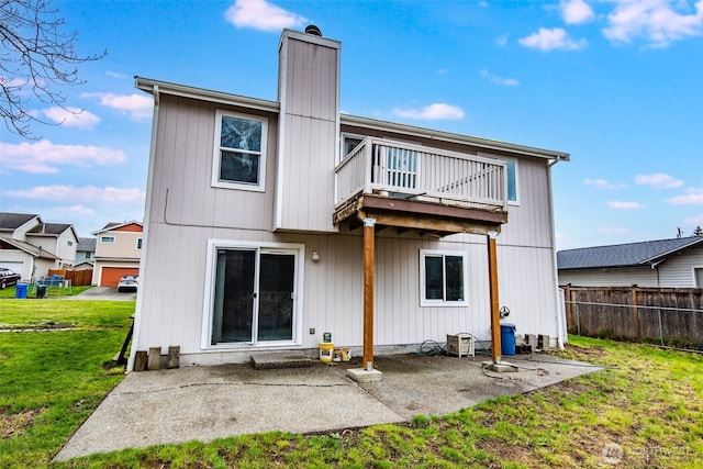 back of house with a balcony, fence, a yard, a chimney, and a patio area