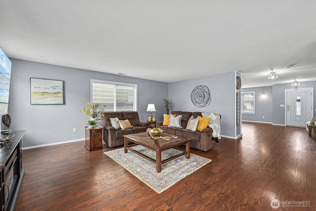 living area with baseboards, plenty of natural light, and dark wood-type flooring