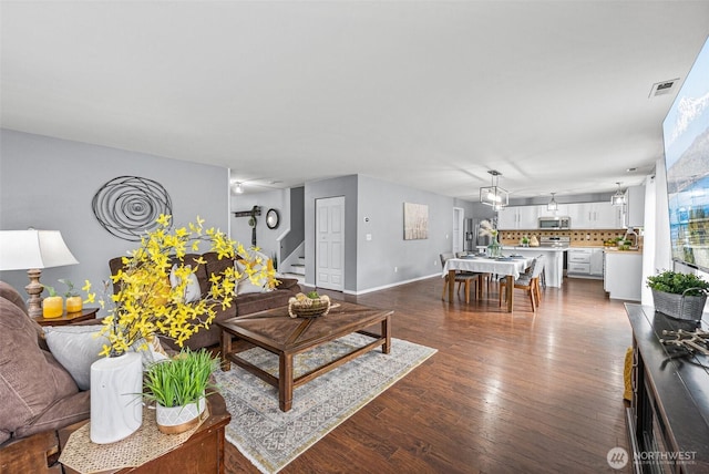 living room featuring visible vents, stairway, baseboards, and dark wood-style flooring