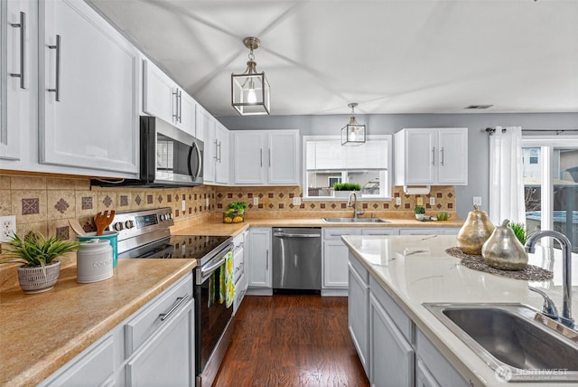 kitchen featuring a sink, decorative backsplash, dark wood-type flooring, and appliances with stainless steel finishes