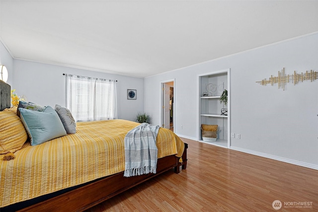 bedroom featuring ornamental molding, baseboards, and wood finished floors