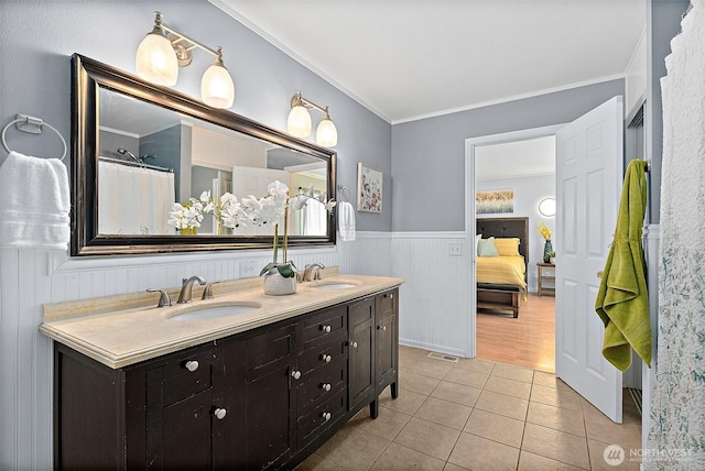 full bathroom featuring tile patterned floors, connected bathroom, wainscoting, and a sink