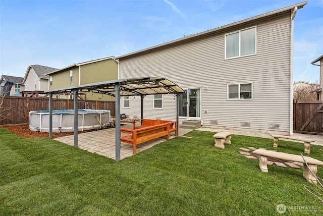 back of house featuring a fenced in pool, fence, entry steps, a lawn, and a patio area