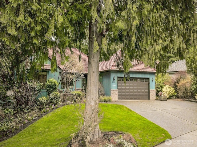 view of front of house with a garage, brick siding, concrete driveway, and a front lawn