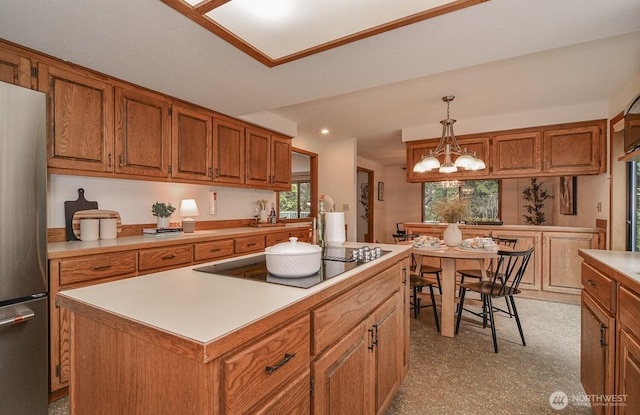 kitchen with black electric stovetop, brown cabinetry, and freestanding refrigerator