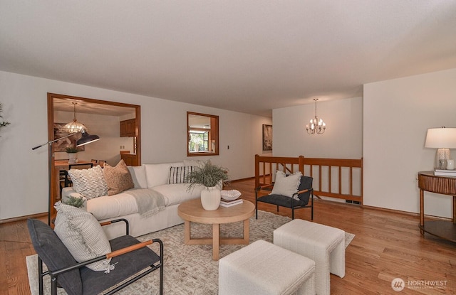 living room featuring light wood-style floors, baseboards, and a chandelier