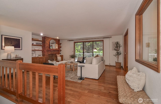 living area featuring light wood finished floors and a brick fireplace