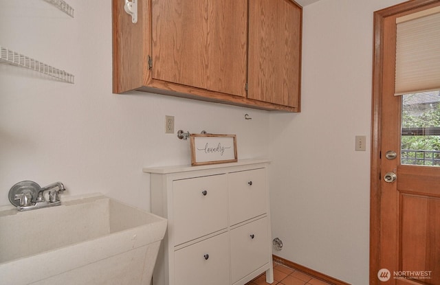 clothes washing area featuring laundry area, baseboards, and a sink