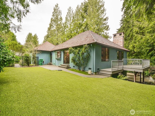 back of property featuring a yard, a deck, a chimney, and entry steps