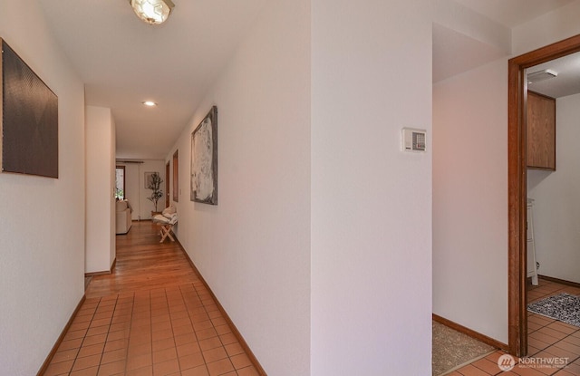 corridor with light tile patterned floors and baseboards