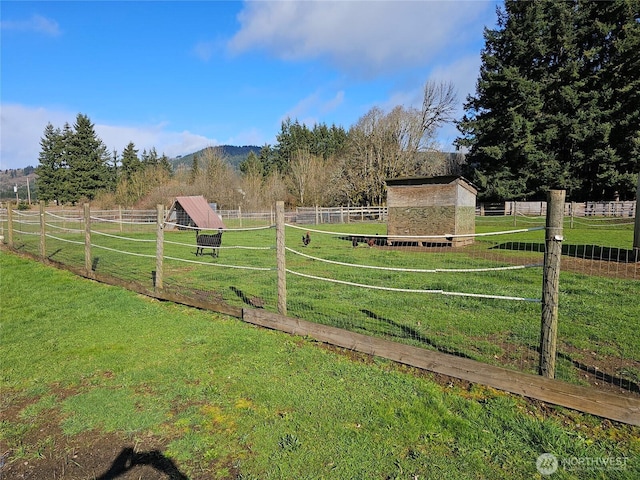 surrounding community with a yard, an outbuilding, a rural view, and fence