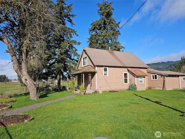 view of home's exterior with metal roof, a lawn, and fence