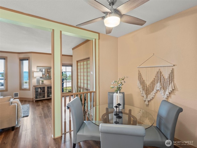 dining room with visible vents, ornamental molding, a ceiling fan, wood finished floors, and baseboards