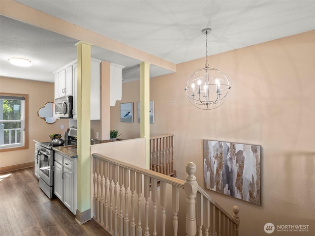 kitchen with baseboards, dark wood finished floors, appliances with stainless steel finishes, a notable chandelier, and white cabinetry