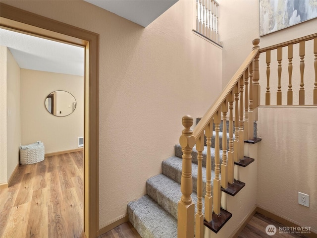 stairs featuring visible vents, wood finished floors, and baseboards