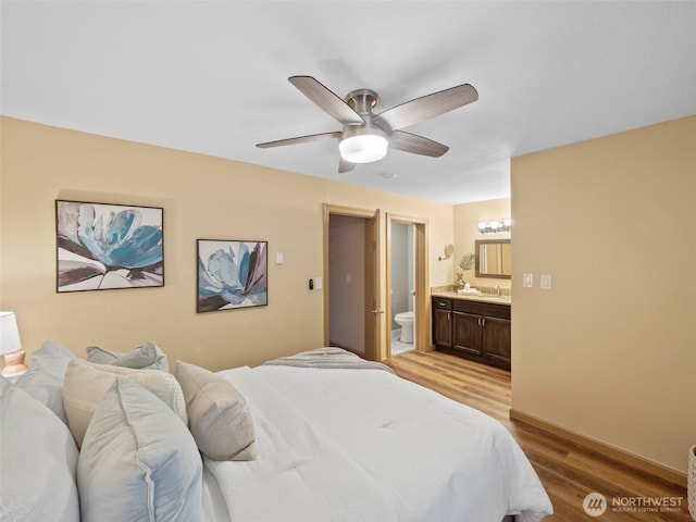 bedroom featuring a sink, ceiling fan, light wood finished floors, and connected bathroom