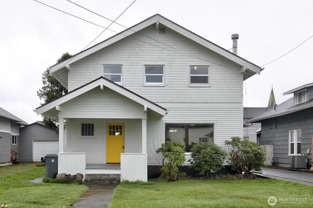 view of front of house featuring a porch, an outbuilding, a front yard, and central AC