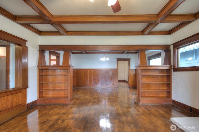 unfurnished room featuring baseboards, coffered ceiling, dark wood finished floors, beam ceiling, and wainscoting