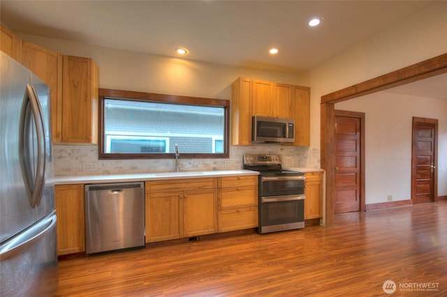 kitchen with a sink, backsplash, appliances with stainless steel finishes, and light countertops