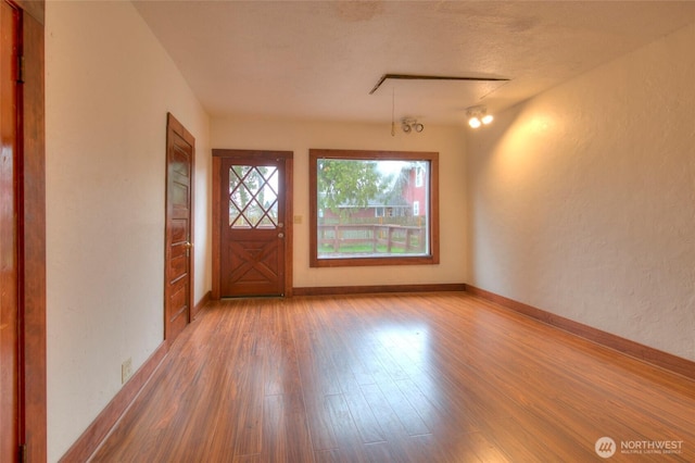 entryway featuring baseboards, wood finished floors, and a textured wall