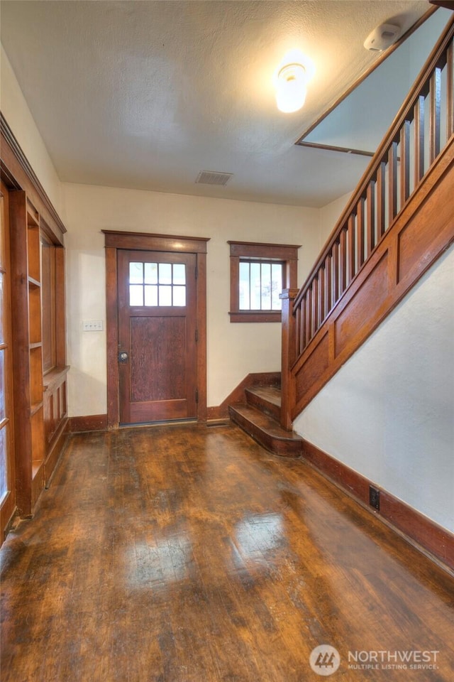 entryway featuring stairway, dark wood-style floors, visible vents, baseboards, and a textured ceiling