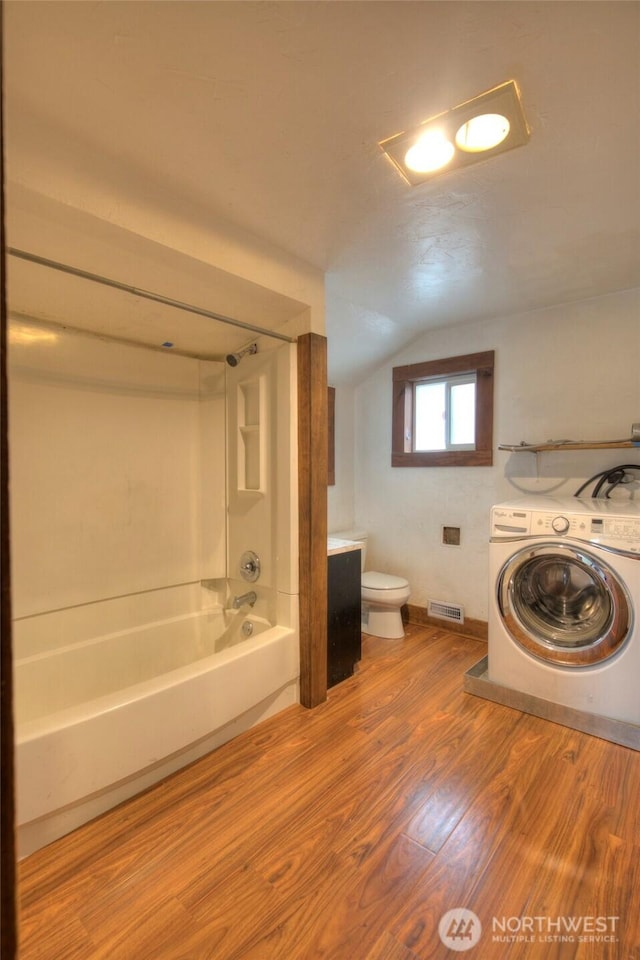 bathroom featuring visible vents, toilet, washer / clothes dryer, shower / tub combination, and wood finished floors