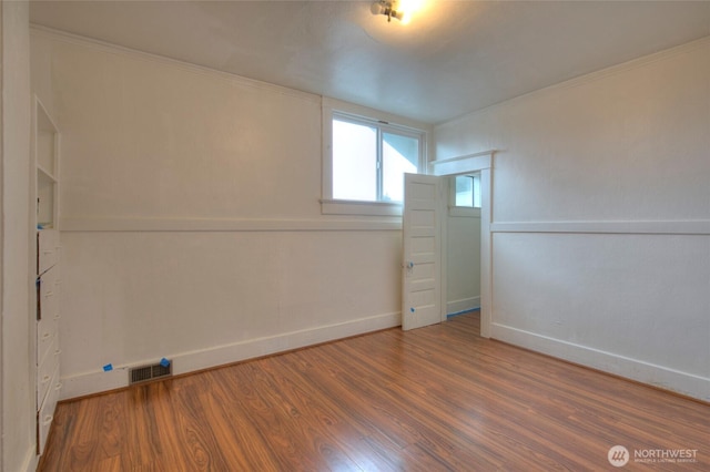 spare room featuring visible vents, wood finished floors, and baseboards