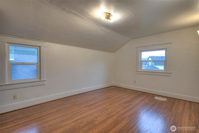 additional living space featuring lofted ceiling, wood finished floors, baseboards, and visible vents