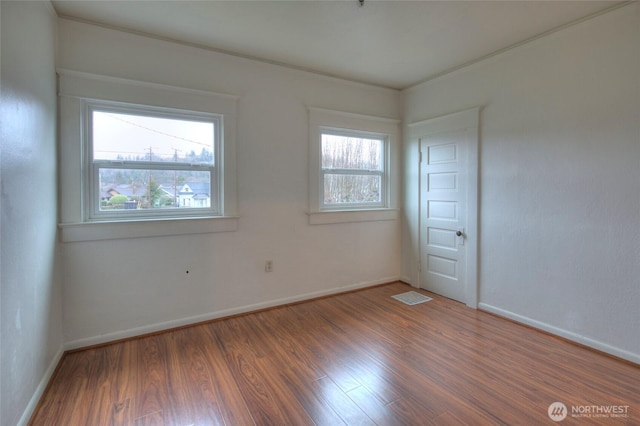 unfurnished room featuring a wealth of natural light, visible vents, and wood finished floors