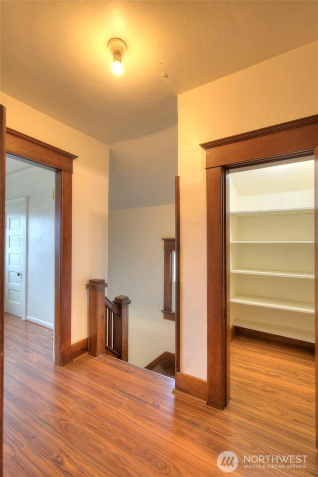 interior space featuring wood finished floors, an upstairs landing, and baseboards