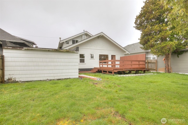 back of property featuring a deck, a yard, and fence